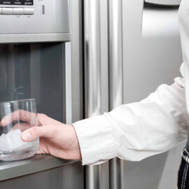 imagem de uma mulher pegando água direto no sipenser da geladeira